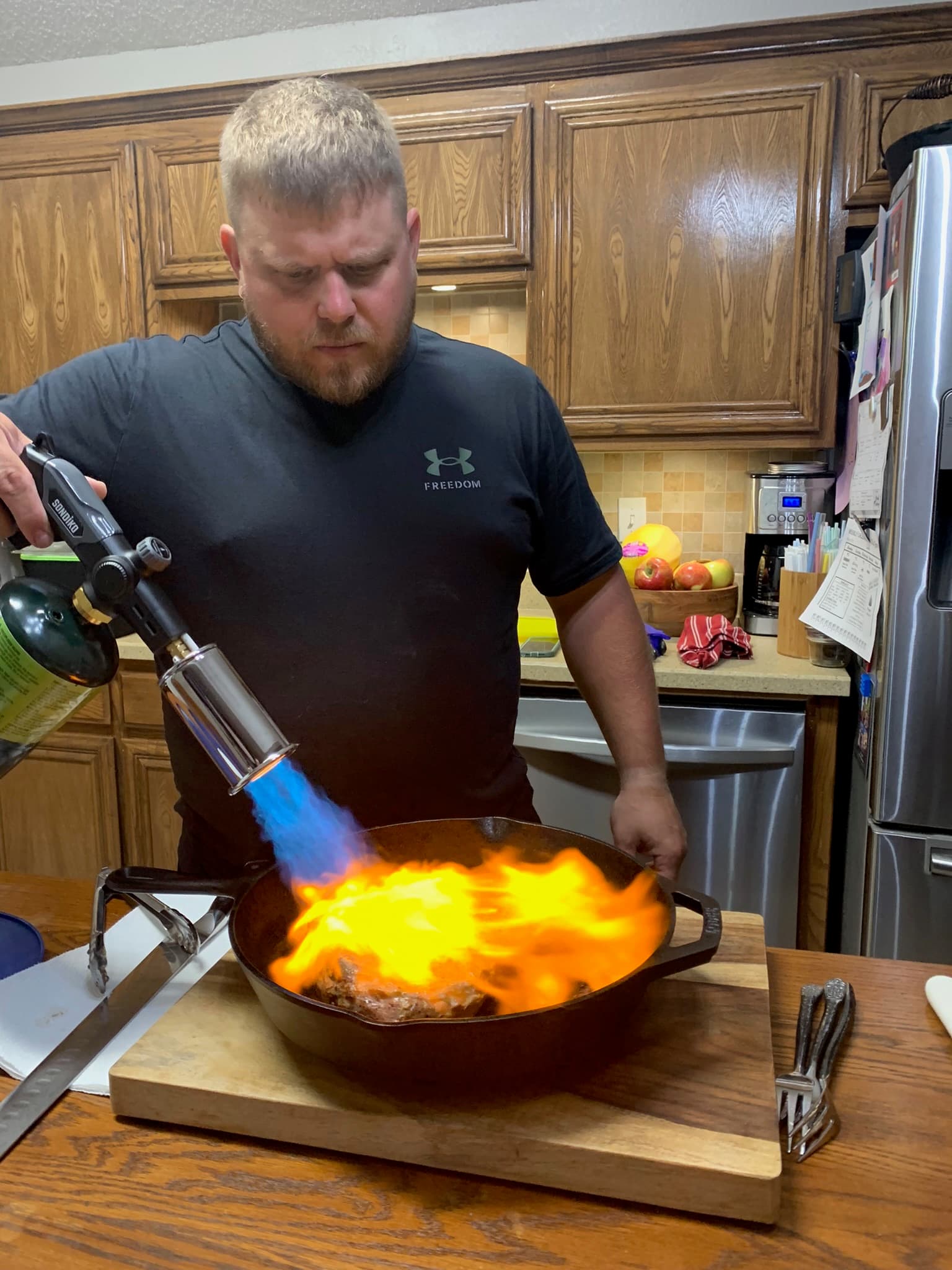 Searing a steak with a blowtorch in a cast iron pan