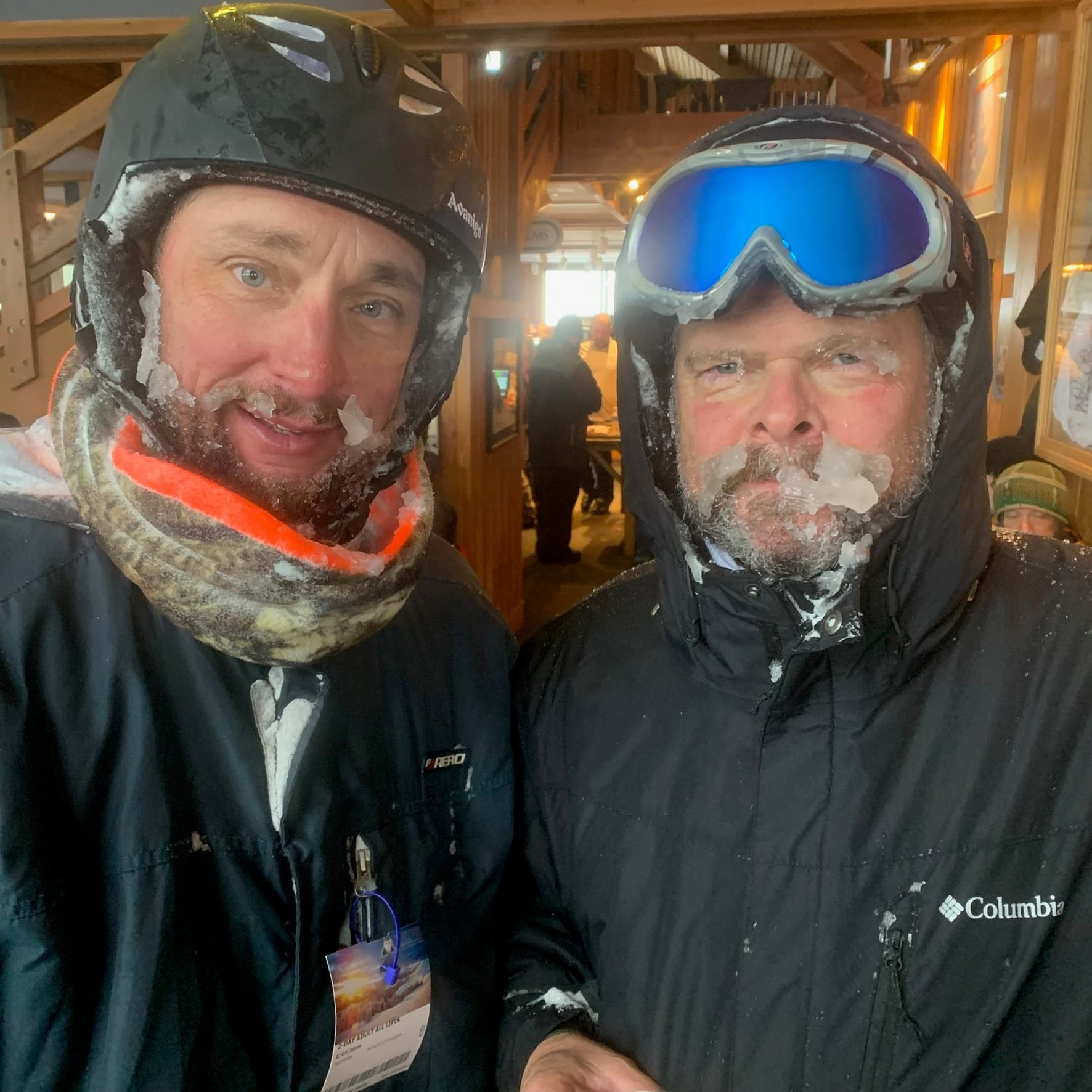 Two skiers indoors with ice caked beards