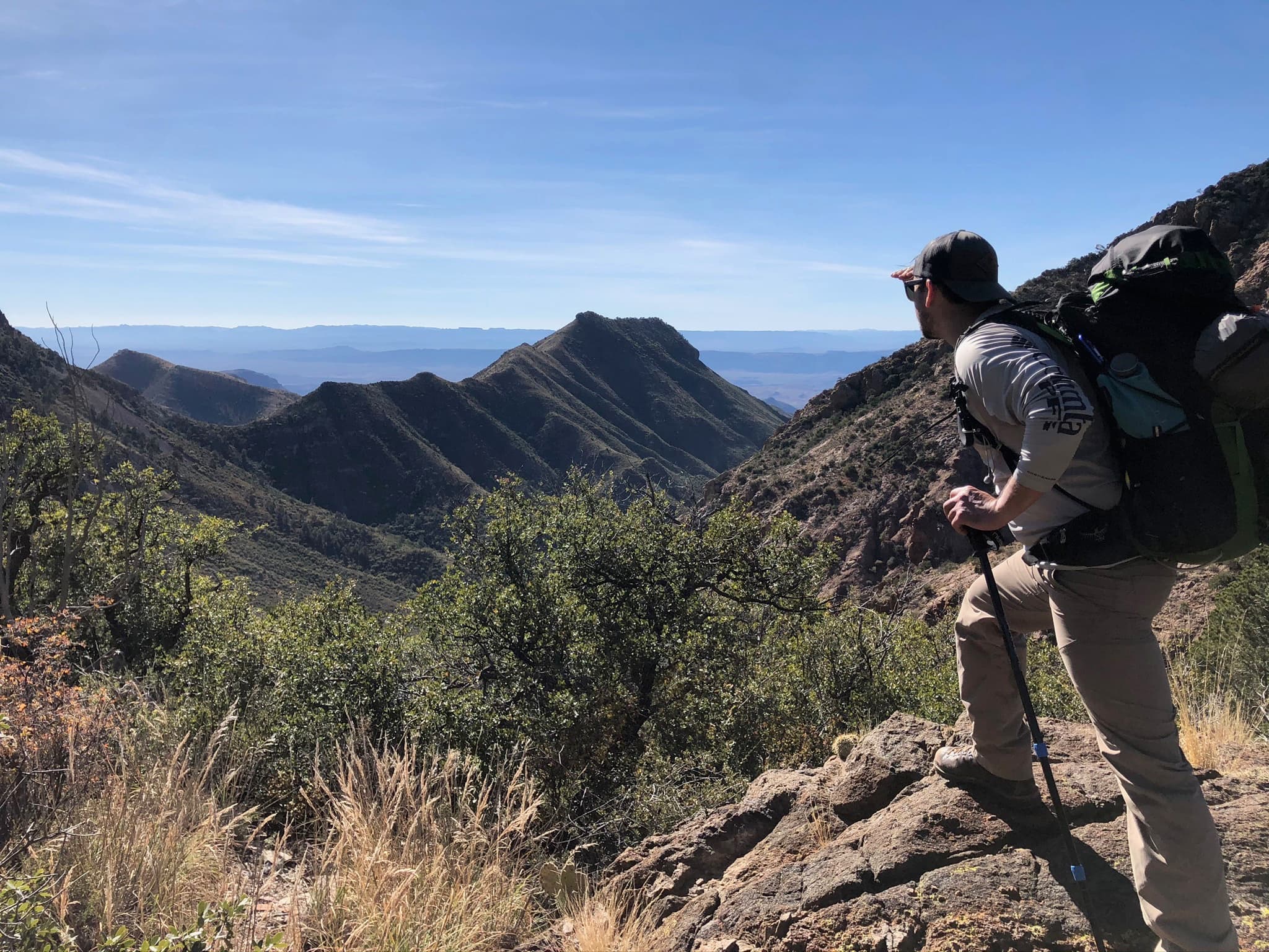 Backpacker glassing a desert canyon system
