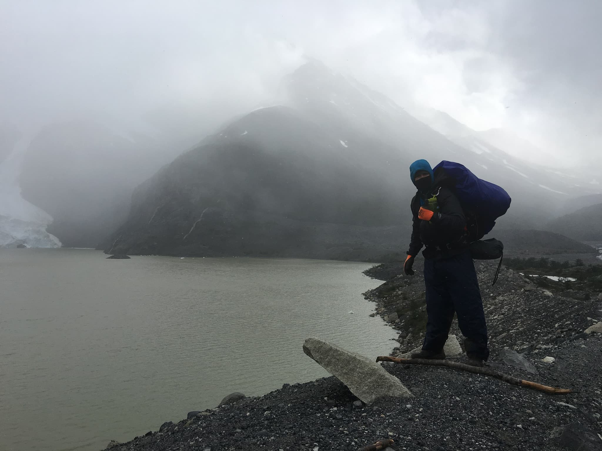 Solo hiker in a storm above a glacial lake