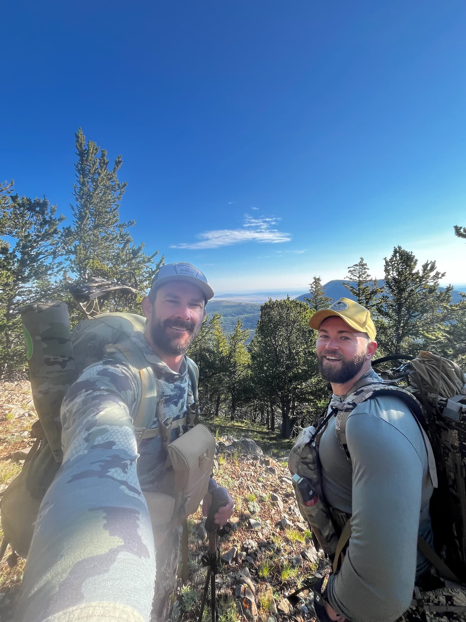 Two backpackers on a ridge under bluebird sky