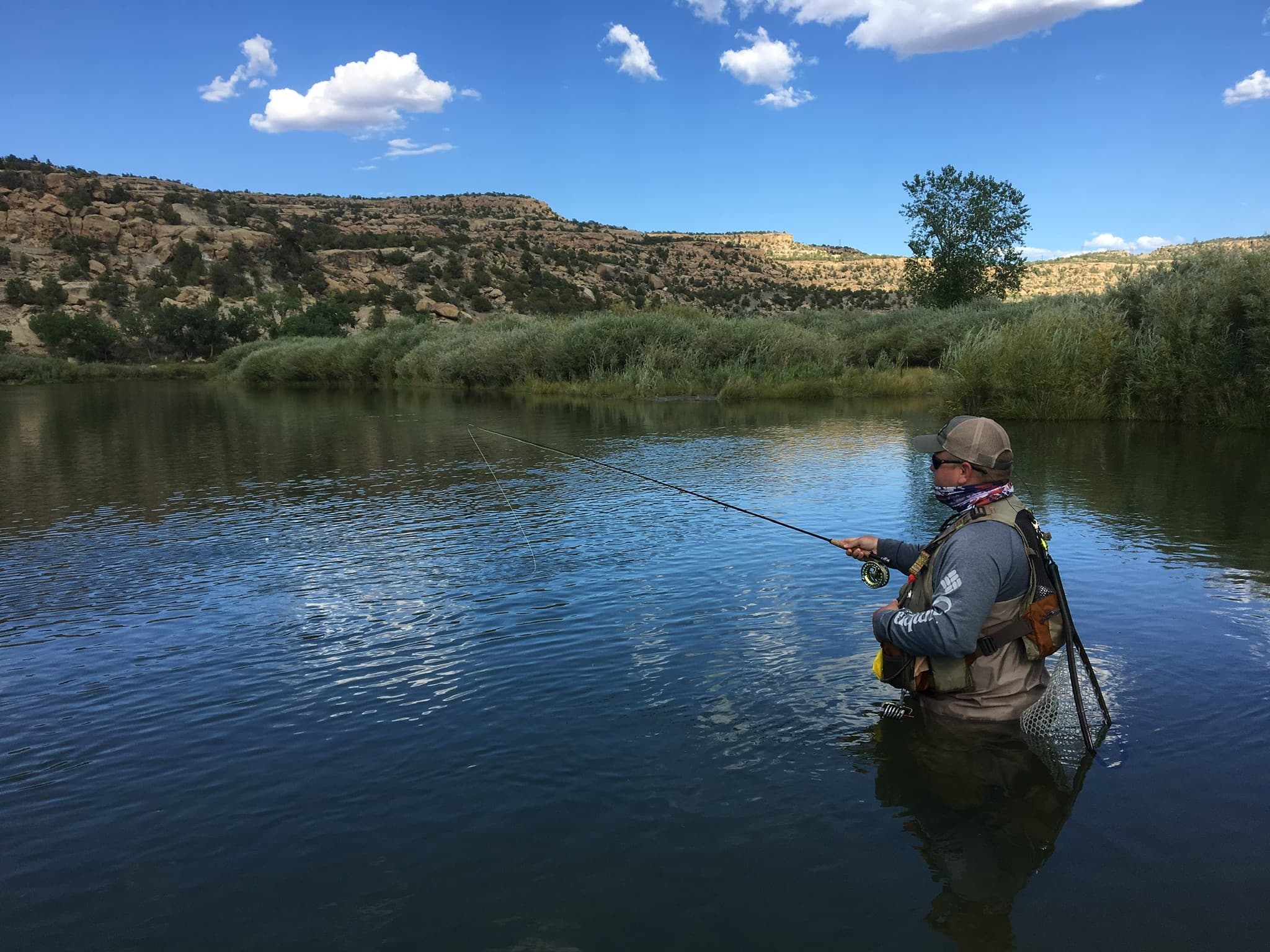 Fly angler casting on a glassy desert tailwater under big sky