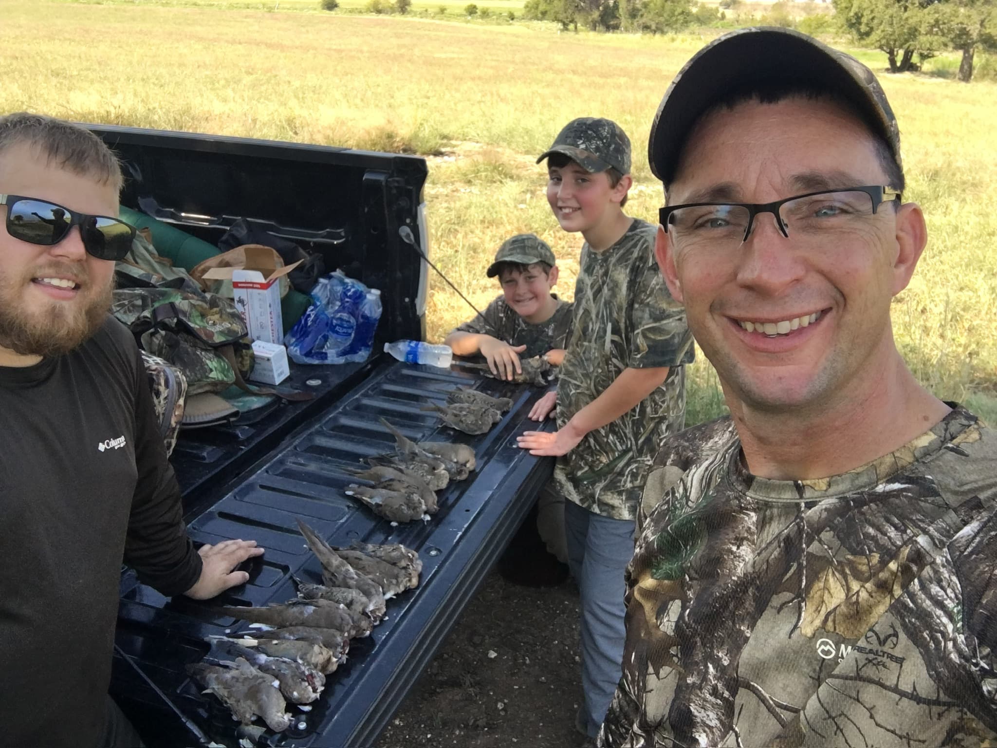 Dad and two boys on a dove hunt tailgate with the day’s birds