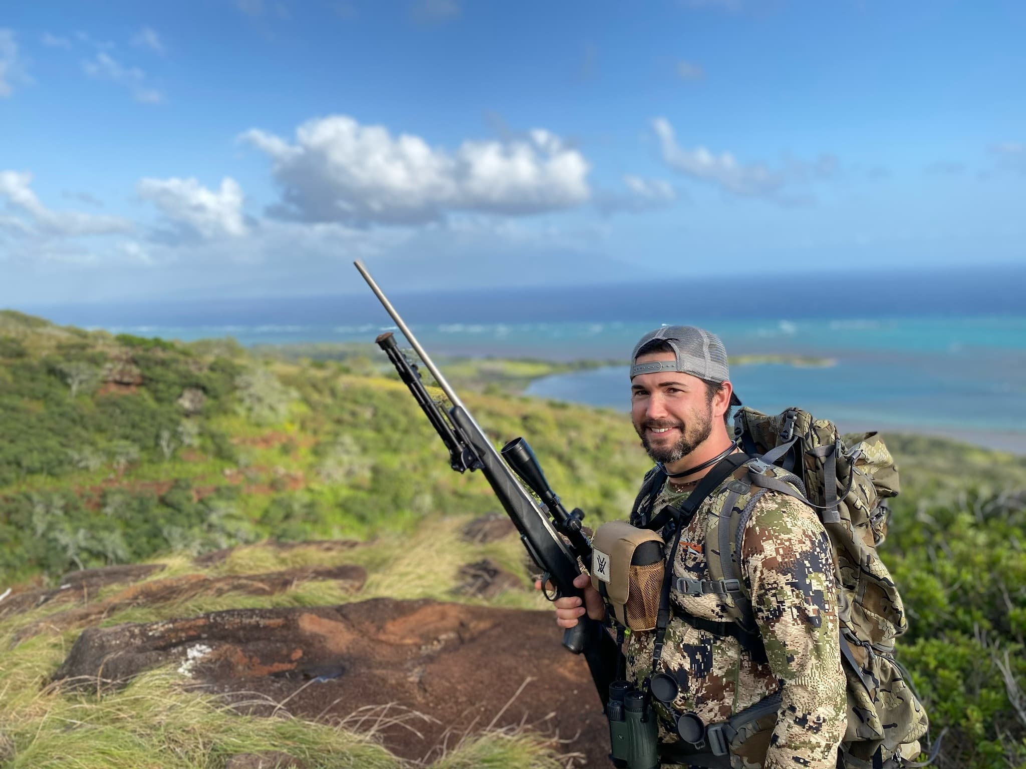 Hunter with rifle on a coastline ridge
